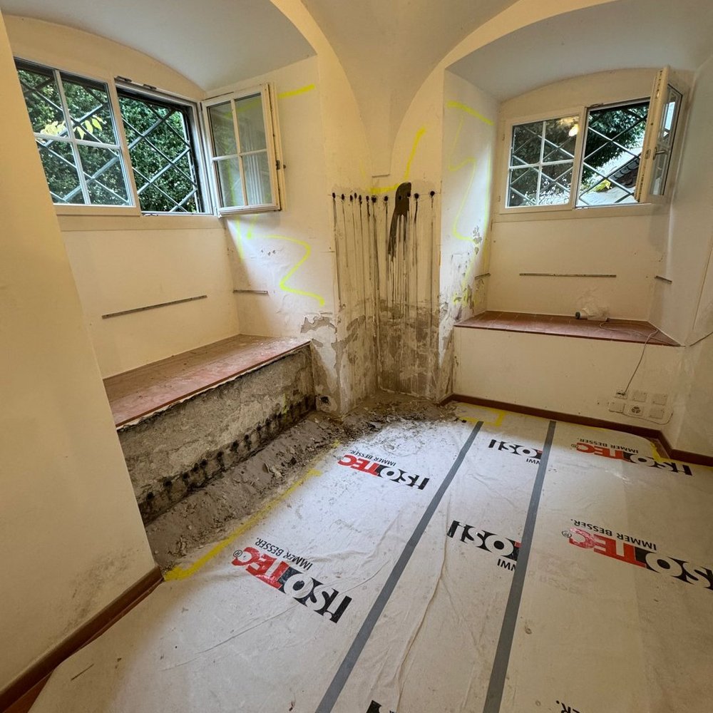 ISOTEC Baustelle mit freigelegter feuchter Wandzone und Bohrlöchern im Zimmer