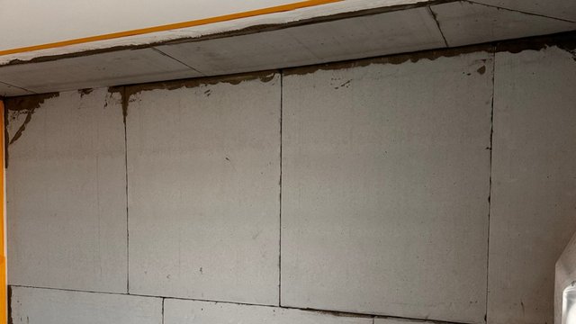 Helle Plattenverkleidung mit sichtbaren Fugen an Wand und Decke, Flecken am Rand