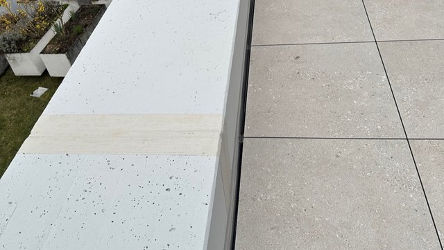 Abgeklebter weißer Betonrand neben grauen Terrassenplatten, Nahaufnahme
