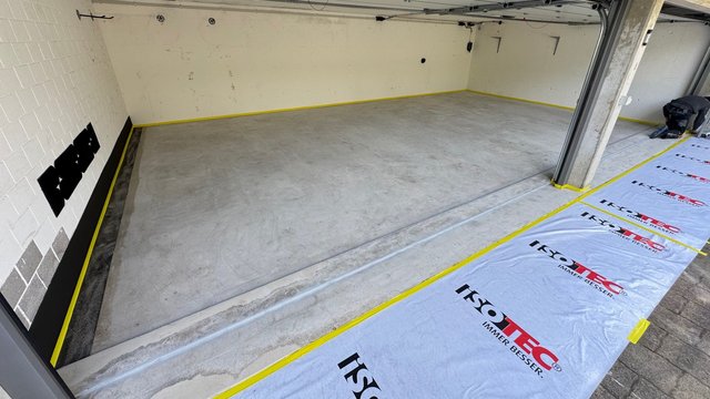 Abgeklebter Betonboden in Garage, Folienabdeckung mit ISOTEC-Logo am Rand