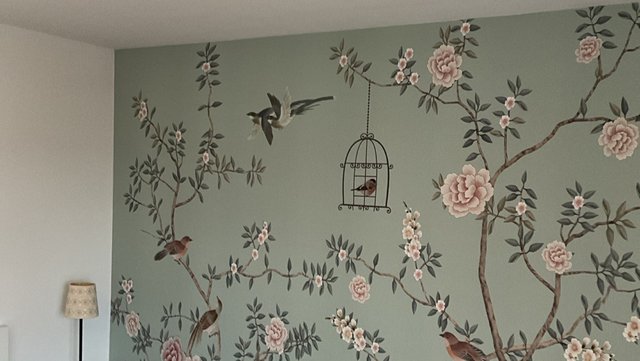 Grünliche Tapetenwand mit Blütenzweigen, Vögeln und hängendem Vogelkäfig