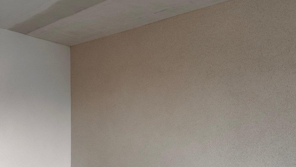 Zimmerwand mit dunklem Feuchtigkeitsfleck nahe der Decke