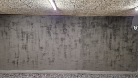 Graue beschichtete Kellerwand mit Rohrdurchführung, Frontalansicht
