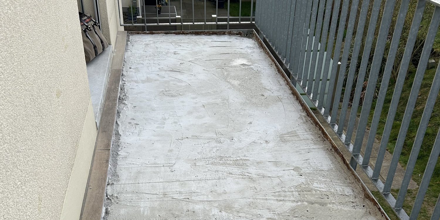 Balkon mit freigelegtem, rauem Betonboden und Metallgeländer