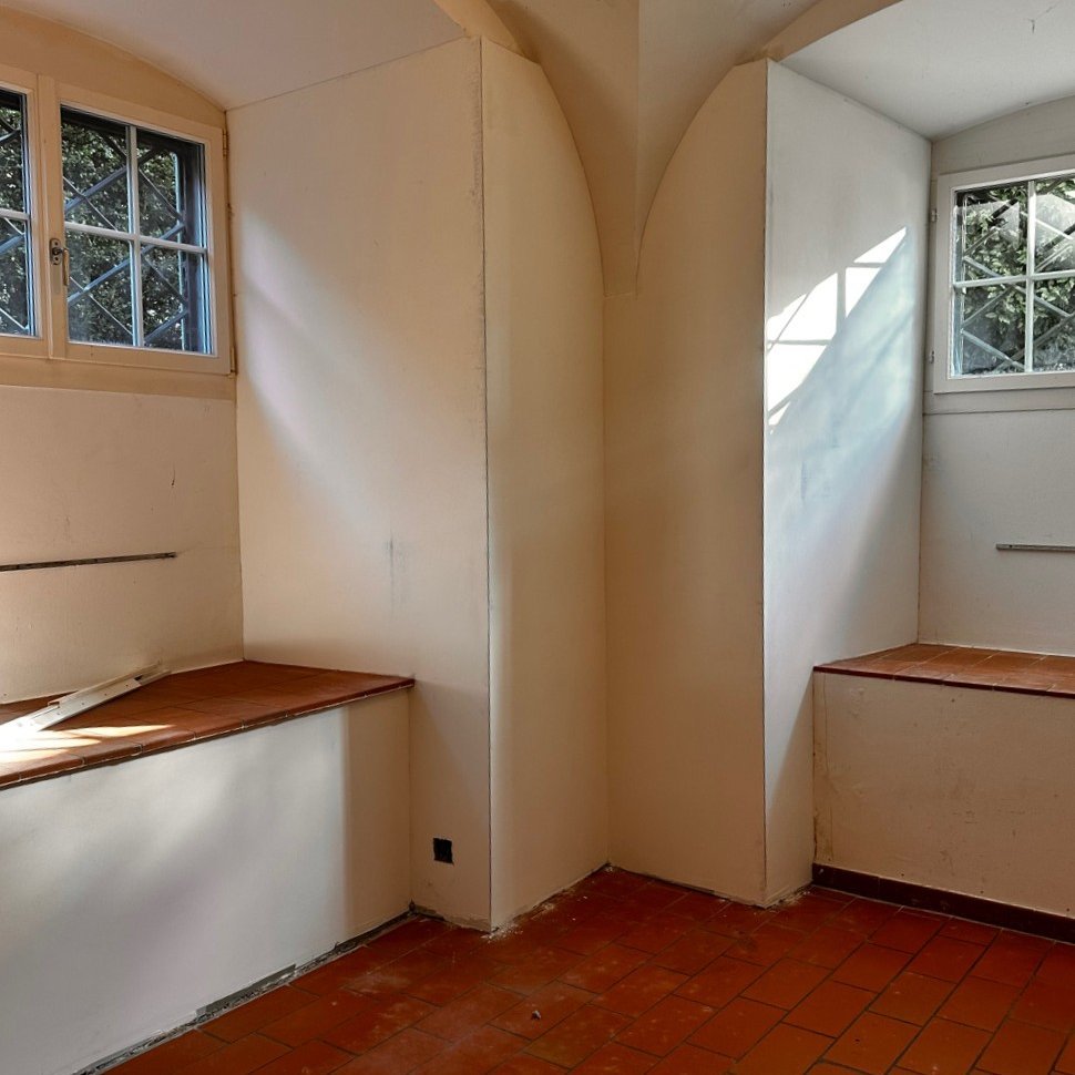 Leerer Raum mit Gewölbedecke, zwei Fenstern und rotem Fliesenboden