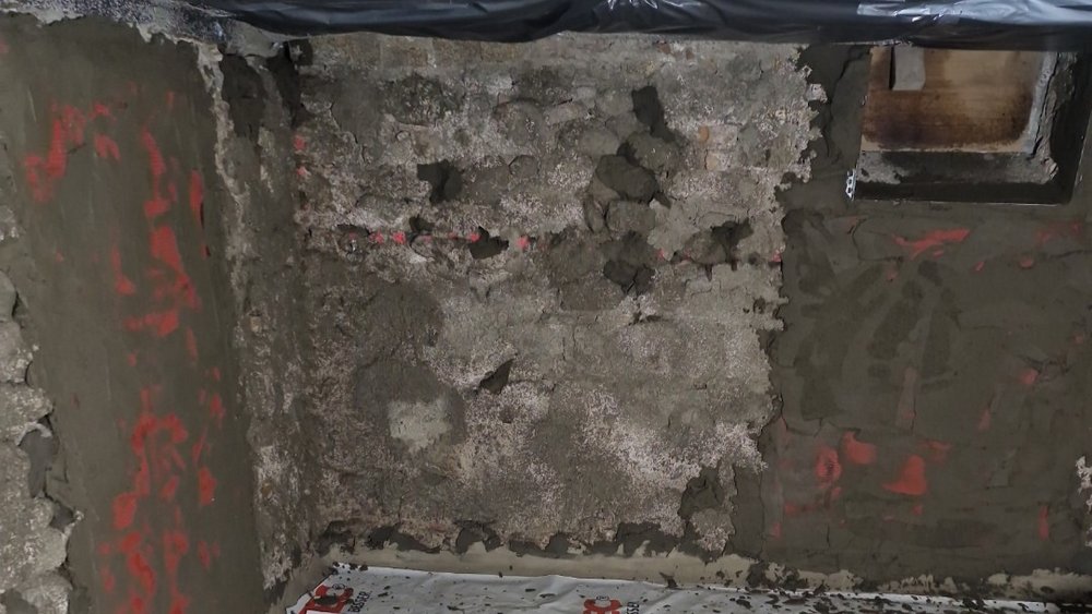 Stark beschädigte Kellerwand mit bröckelnder Oberfläche