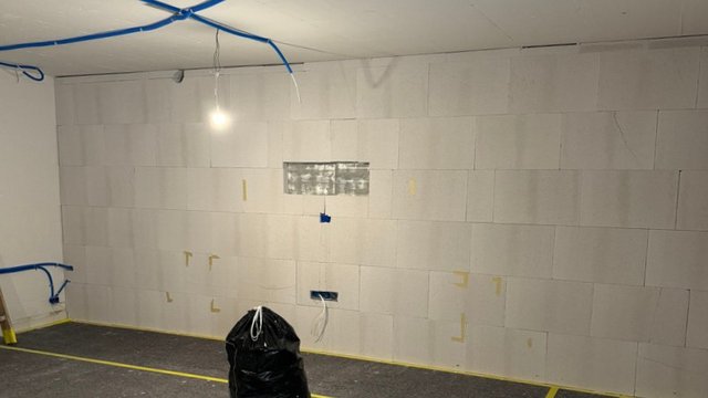 Helle Platten an Kellerwand montiert, Kabel hängen von der Decke