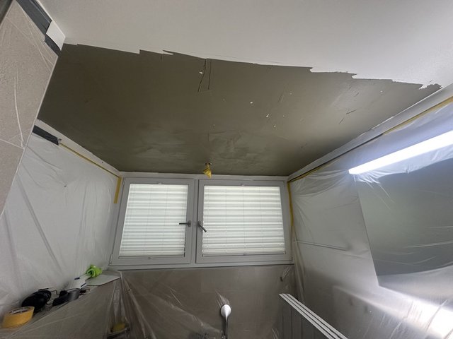 Abgeklebter Raum mit Folienabdeckung, Decke mit grauer Masse beschichtet.
