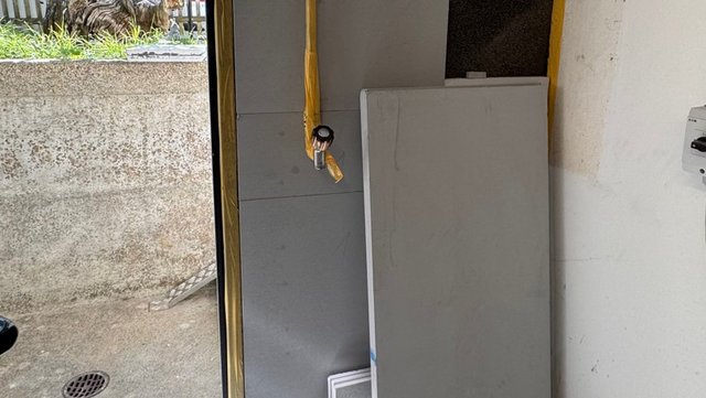 Graue Platten an Wand, Rohr mit gelbem Klebeband geschützt, Türöffnung abgeklebt