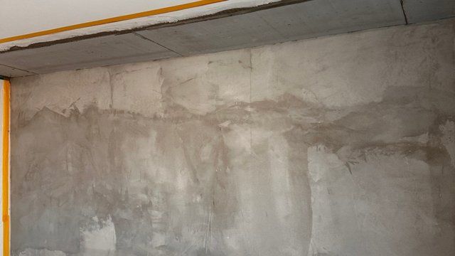 Feuchteflecken und Verfärbungen an grauer Kellerwand unter Betondecke