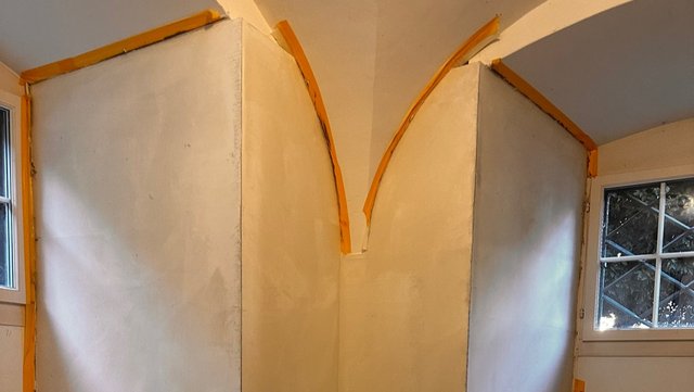 Helle Platten an verkleideter Raumecke mit orangefarbenen Randstreifen