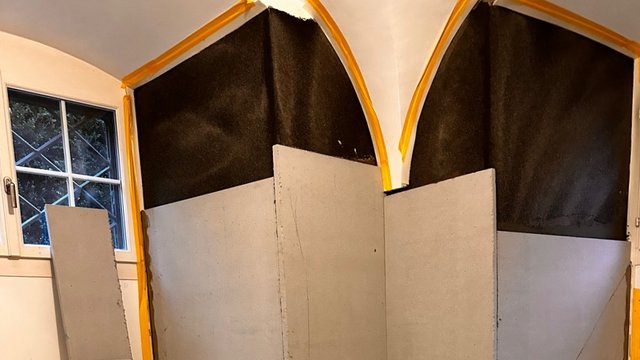 Helle Platten vor schwarzer Bahn an Wand und Gewölbebögen im Raum