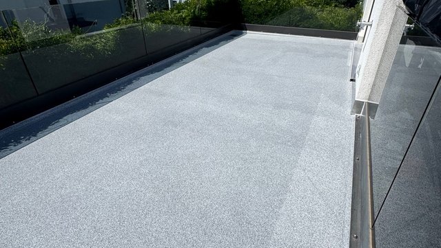Balkon mit grauer Abdichtungsfläche und Glasgeländer, Blick über die Fläche