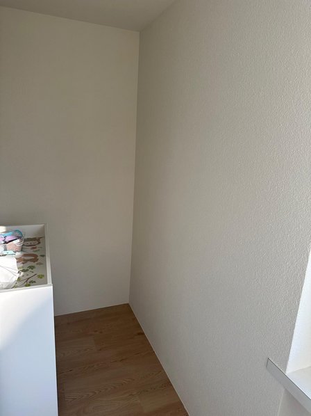 Helle Zimmerecke mit glatter Wand und Holzfußboden