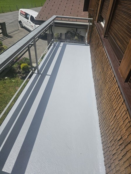 Balkon mit heller Beschichtung und Metallgeländer an Hausfassade