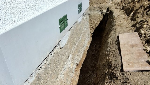 Freigelegte Kellerwand mit Erdgraben entlang des Gebäudes