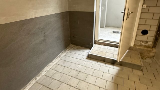 Gefliester Kellerraum mit dunkelgrauer Beschichtung bis zur halben Wandhöhe