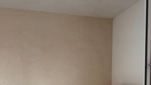 Zimmerdeckenecke mit beiger Tapete und weißer Wand, Nahaufnahme
