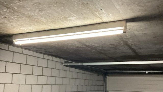 Deckenleuchte in Garage, Beton­decke mit dunkler Verfärbung über Mauerwerk.