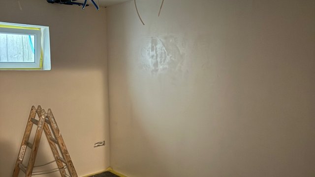 Leerer Raum mit glatter Wand, Leiter und kleinem Fenster