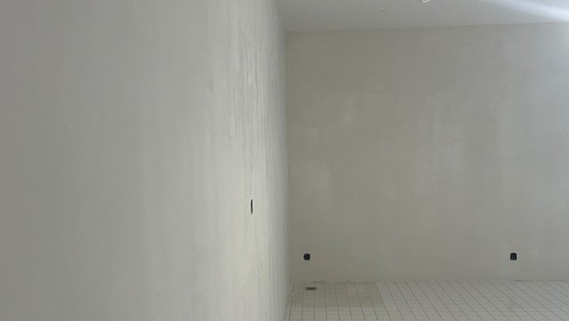Leerer Raum mit weißen Wänden und gefliestem Boden