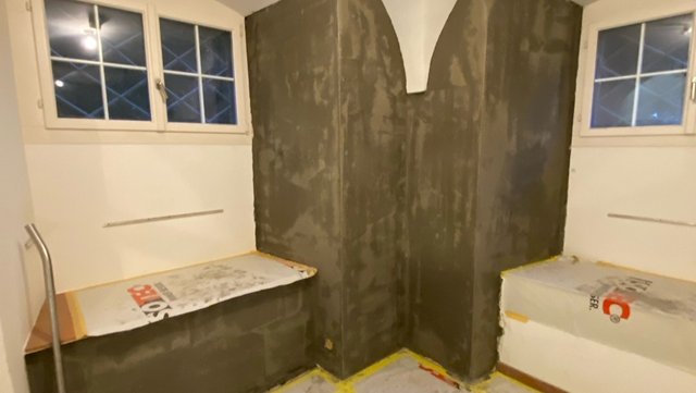 Schwarze Masse an Kellerwänden und Sockeln zwischen zwei Fenstern