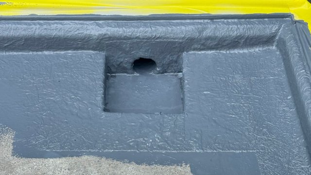 Graue Masse auf rechteckiger Fläche mit Aussparung, oben gelbe Folienkante