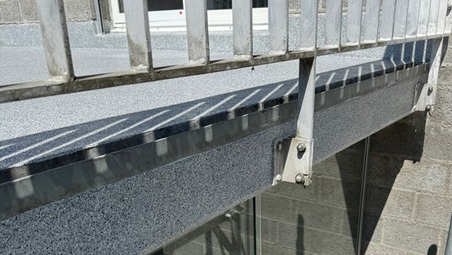 Metallgeländer über grauer Balkonkante, Nahaufnahme