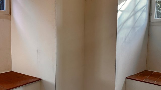 Leerer Raum mit weißer Wand, Fliesenpodesten und Fenstern