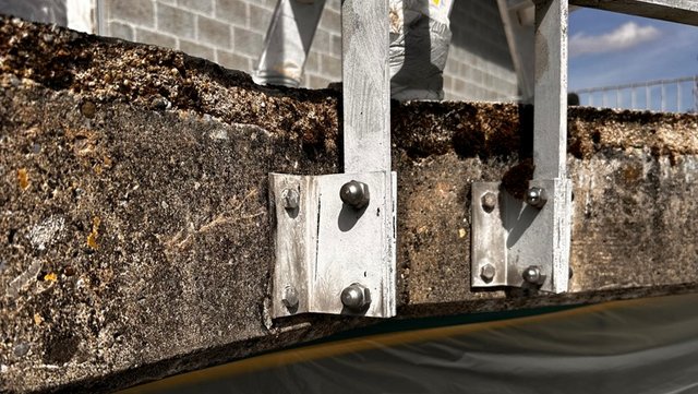 Metallhalterung an bröckelnder Betonkante, Nahaufnahme