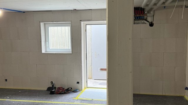 Heller Kellerraum mit heller Platte an den Wänden, Fenster und offener Tür