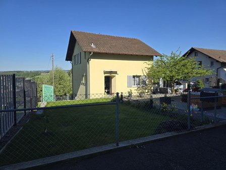 Einfamilienhaus mit Garten, Zaun und gepflastertem Vorplatz