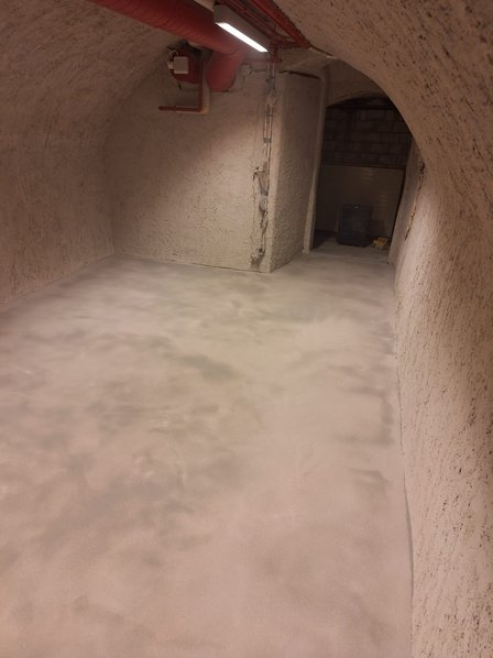 Gewölbekeller mit hellem Bodenbelag und rau verputzten Wänden