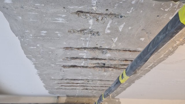 Freigelegte Betondecke mit Schlitzreihen und Ausbrüchen, Nahaufnahme.