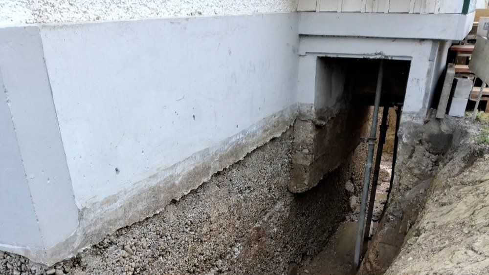 Freigelegte Kellerwand im Erdreich mit abgetragenem Putz und Stützen