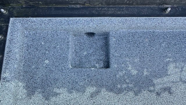 Graue, gesprenkelte Oberfläche mit quadratischer Vertiefung, Nahaufnahme
