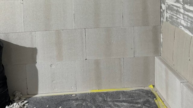 Helle Platten an Wand und Sockel, Ecke mit gerillter grauer Masse
