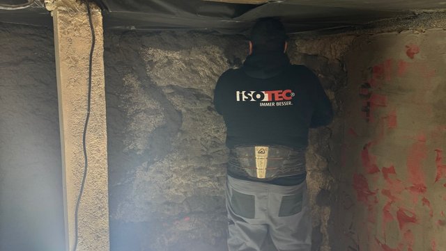 ISOTEC Mitarbeiter prüft raue Steinwand im Keller