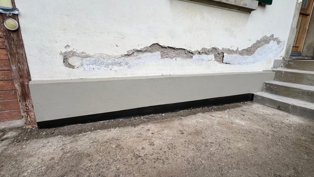 Abgeplatzter Wandputz am Sockelbereich neben Treppe, Nahaufnahme