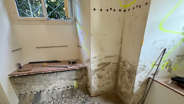 Bohrlöcher und abgeplatzter Putz an Wand in Zimmer, Renovierung