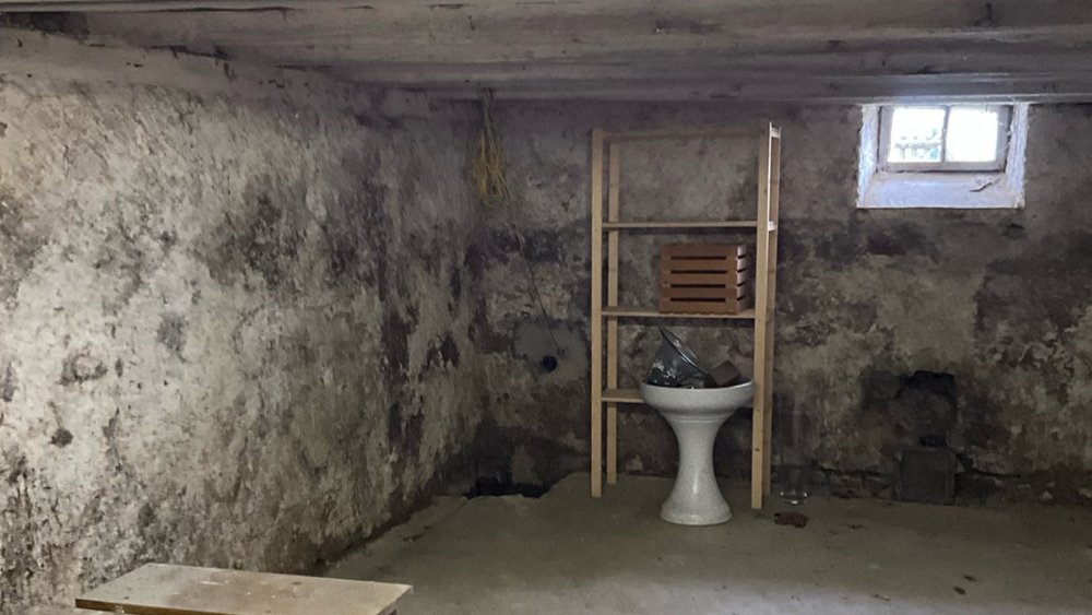 Alter Kellerraum mit rauen Wänden, Regal und kleinem Fenster