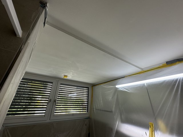Abgeklebte Zimmerdecke über Fensterfront, Möbel mit transparenter Folie geschützt.