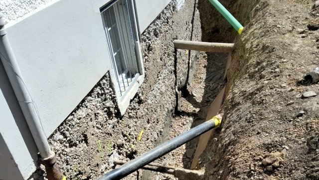 Freigelegte Kellerwand im Erdgraben neben Fenster, Nahaufnahme