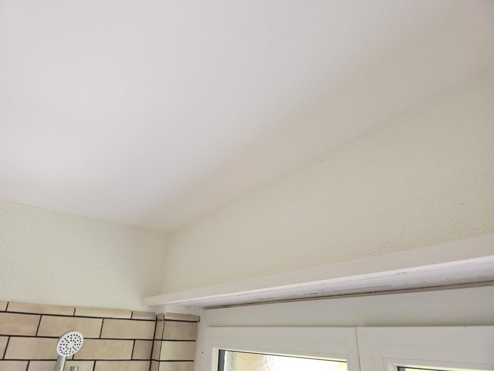 Badezimmerdecke mit gelblichen Verfärbungen über Duschbereich und Fensterrahmen