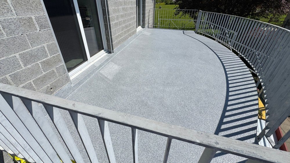 Grauer Balkonboden mit Geländer und Schattenwurf