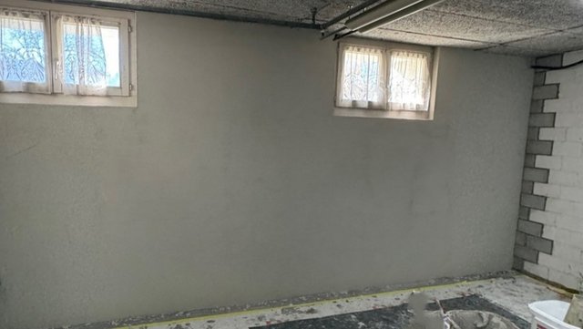 Graue Wand in Kellerraum mit zwei kleinen Fenstern, frisch beschichtet