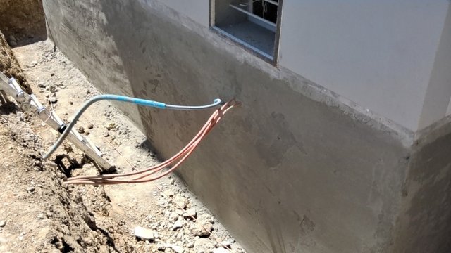 Freigelegte Gebäudewand mit grauer Masse und herausgeführten Leitungen