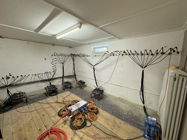 Kellerraum mit Schläuchen an Wandbohrungen und Ventilatoren am Boden