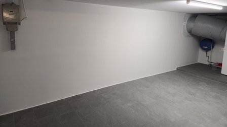 Heller Kellerraum mit weißer Wand, Fliesenboden, Lüftungsrohr und Leuchtstofflampe