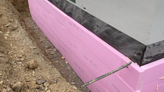 Rosa Dämmplatten an Gebäudesockel im Erdgraben montiert